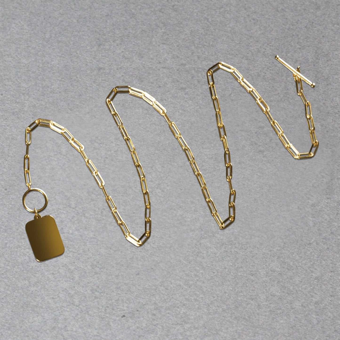 Gold chain necklace with a tag on a gray background