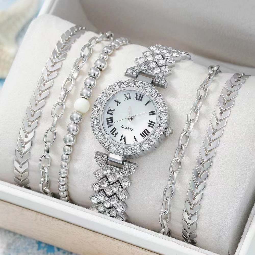 Silver watch and bracelets on a white cushion in a box