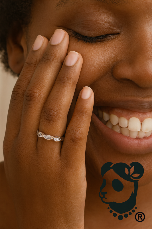 Close-up of a woman with an infinity diamond wedding band on their finger, smiling.