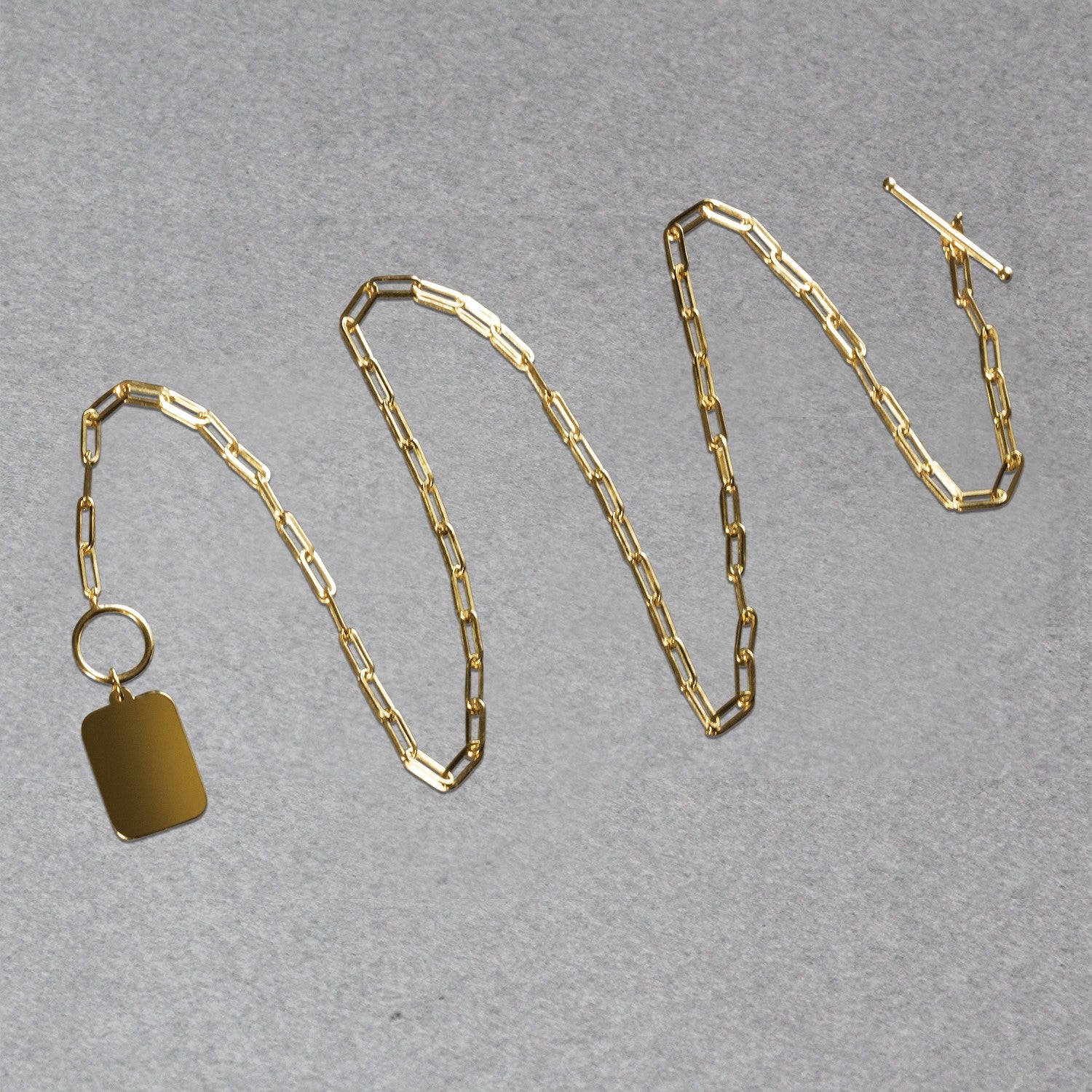 Gold chain necklace with a tag on a gray background