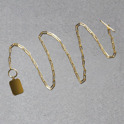 Gold chain necklace with a tag on a gray background
