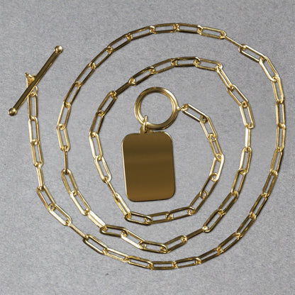 Gold chain necklace with a rectangular pendant on a gray background