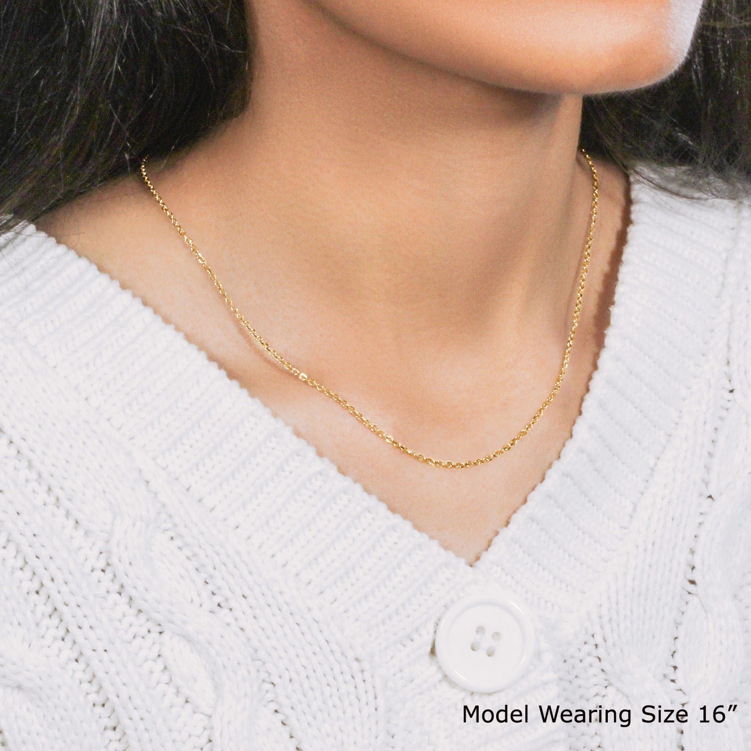 An 18k Yellow Gold Diamond Cut Cable Link Chain necklace worn by a woman wearing a white sweater.