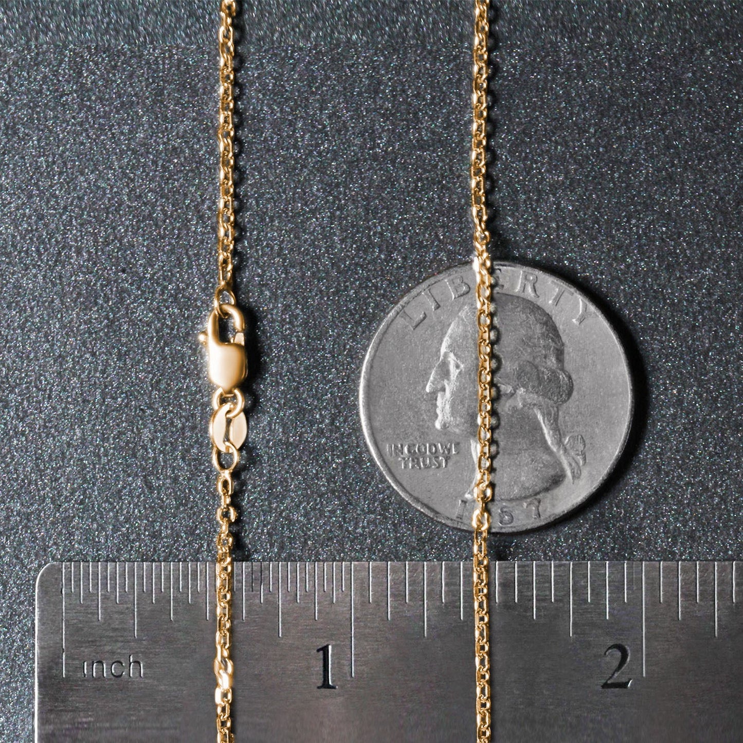 Gold chain next to a quarter and ruler on a dark surface