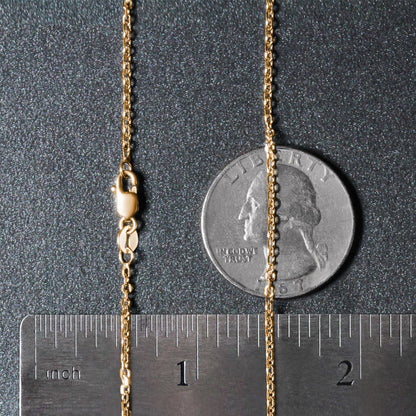 Gold chain next to a quarter and ruler on a dark surface