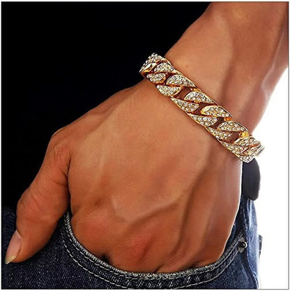 A gold chain bracelet on a man's wrist with his hand in a jean pocket