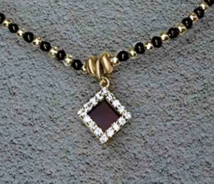 Necklace with a square pendant and black beads on a textured surface