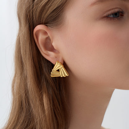 Gold earrings worn by a person with a neutral background