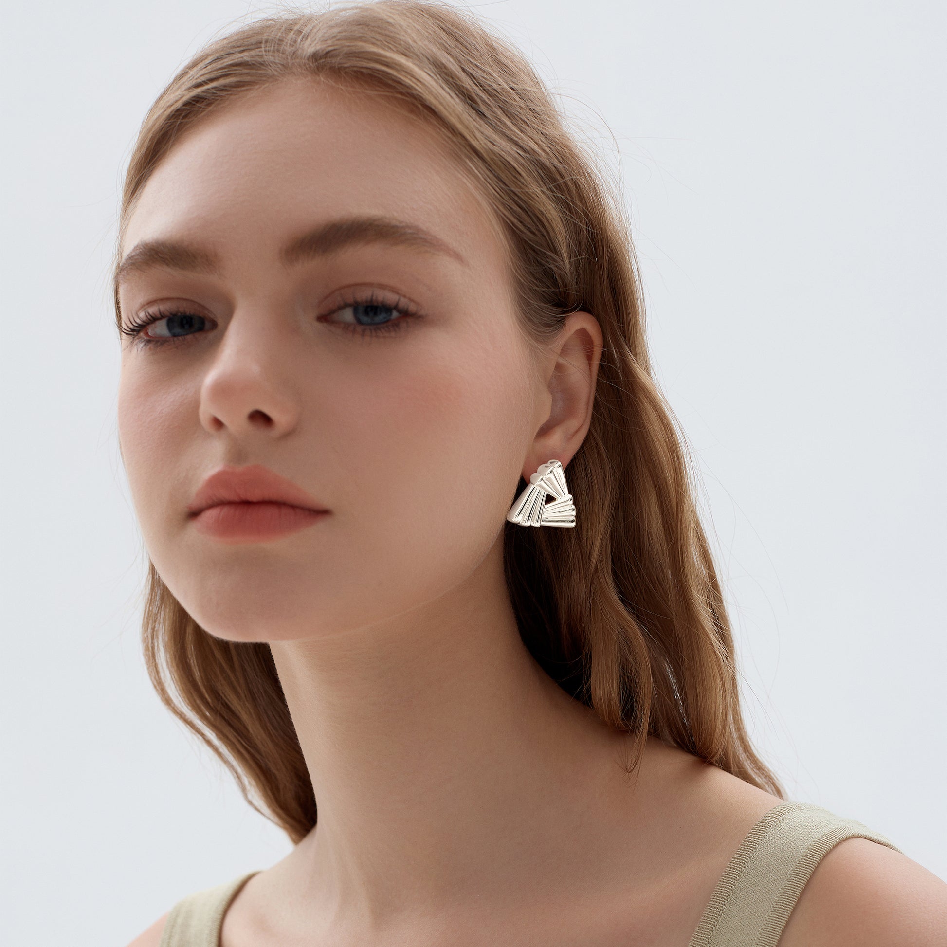 Woman wearing a geometric earring against a plain background