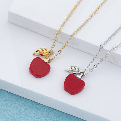 Two necklaces with red apple pendants on a white surface