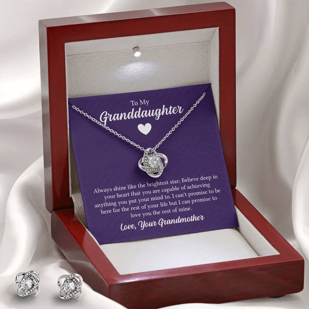 Necklace and earring set featuring elegant love knot designs with sparkling cubic zirconia, displayed in a purple gift box with a heartfelt message for a granddaughter from her grandmother.