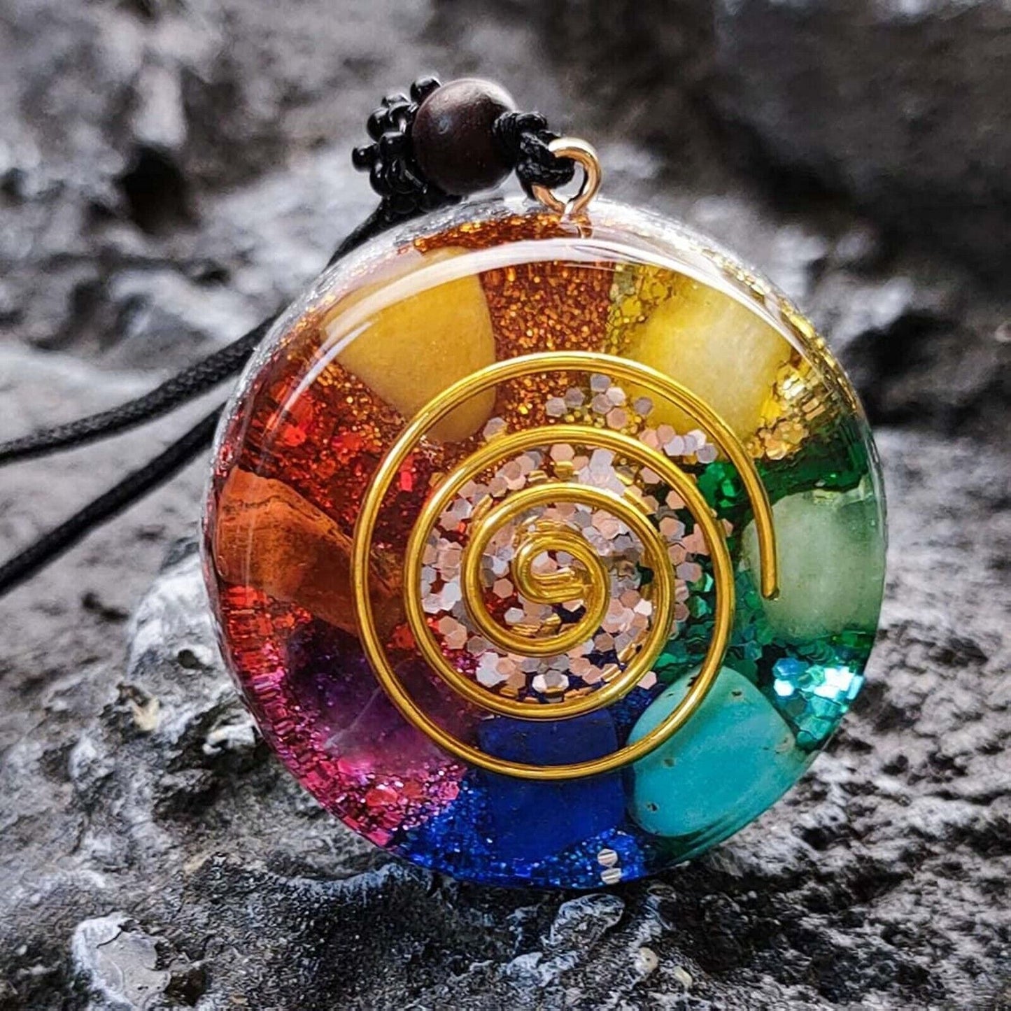 "Colorful chakra energy necklace featuring glittery resin, golden spiral, and crystal accents for spiritual balance."