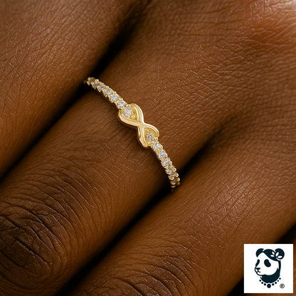 Close-up of an elegant gold infinity ring with sparkling zircon stones on a dark-skinned hand, styled by Panda Jewelry Store.