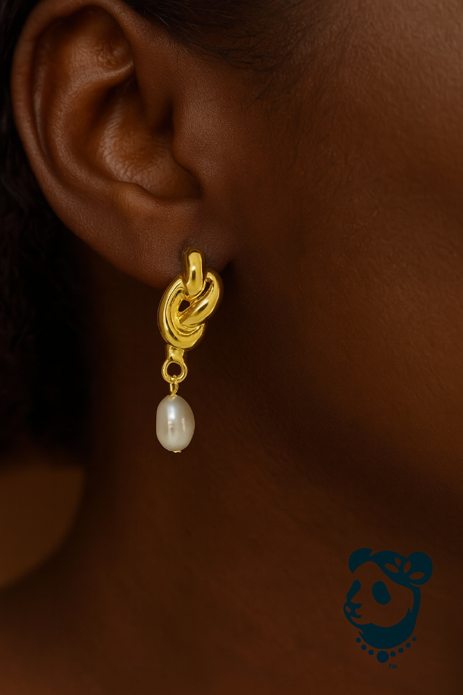 Gold earring with a pearl drop worn by a person